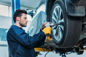 automechanic-unscrewing-tire-bolts-on-a-lifted-up-car-at-a-repair-shop-.jpg