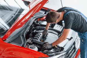 top-view-of-male-worker-in-uniform-that-repairs-red-automobile.jpg